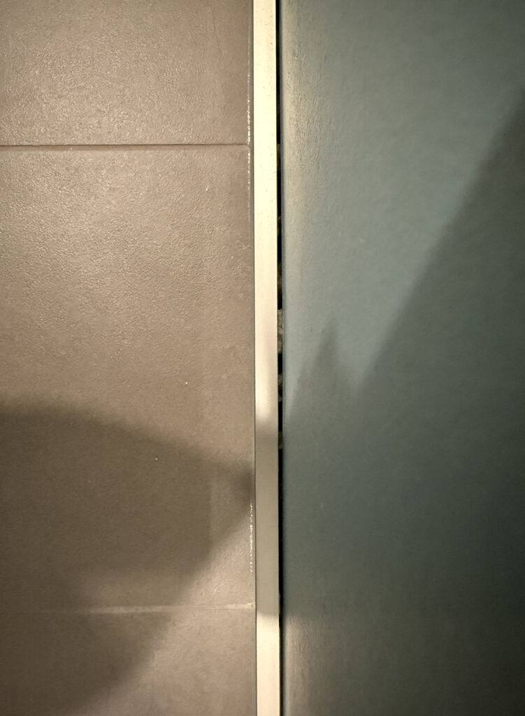 Large gap between the tile baseboard and the wall (you can see the mortar)