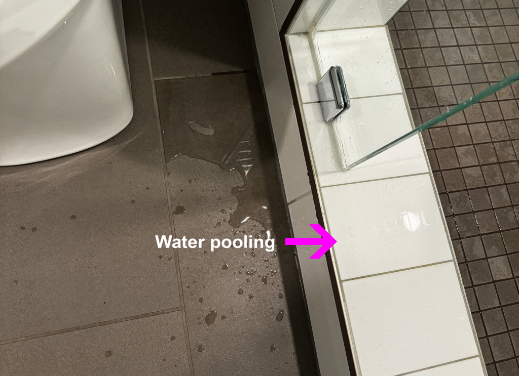 Water pools on shower curb and leaks onto tile floor