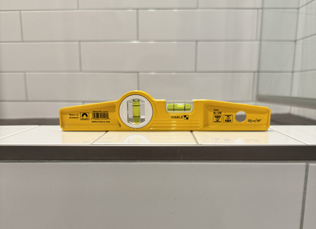 Shower curb installed with no slope causing water to pool